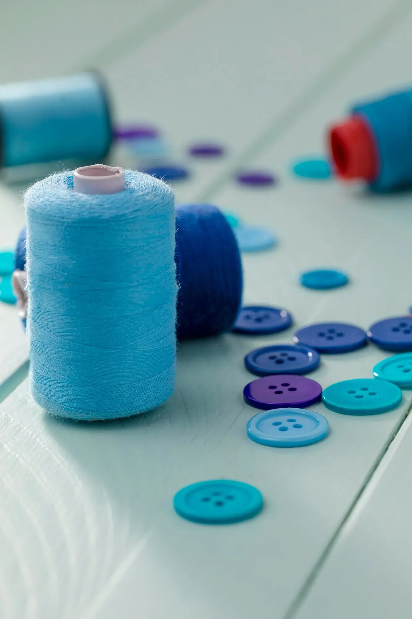 Hochwinkelaufnahme von blauen Knöpfen mit Garnrollen